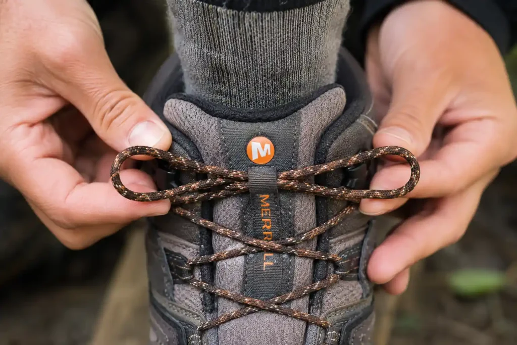 a person's hands demonstrating the heel lock lacing technique on a hiking shoe